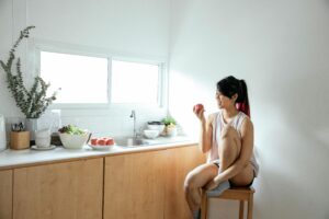 how to improve digestion naturally woman eating apple in bright kitchen