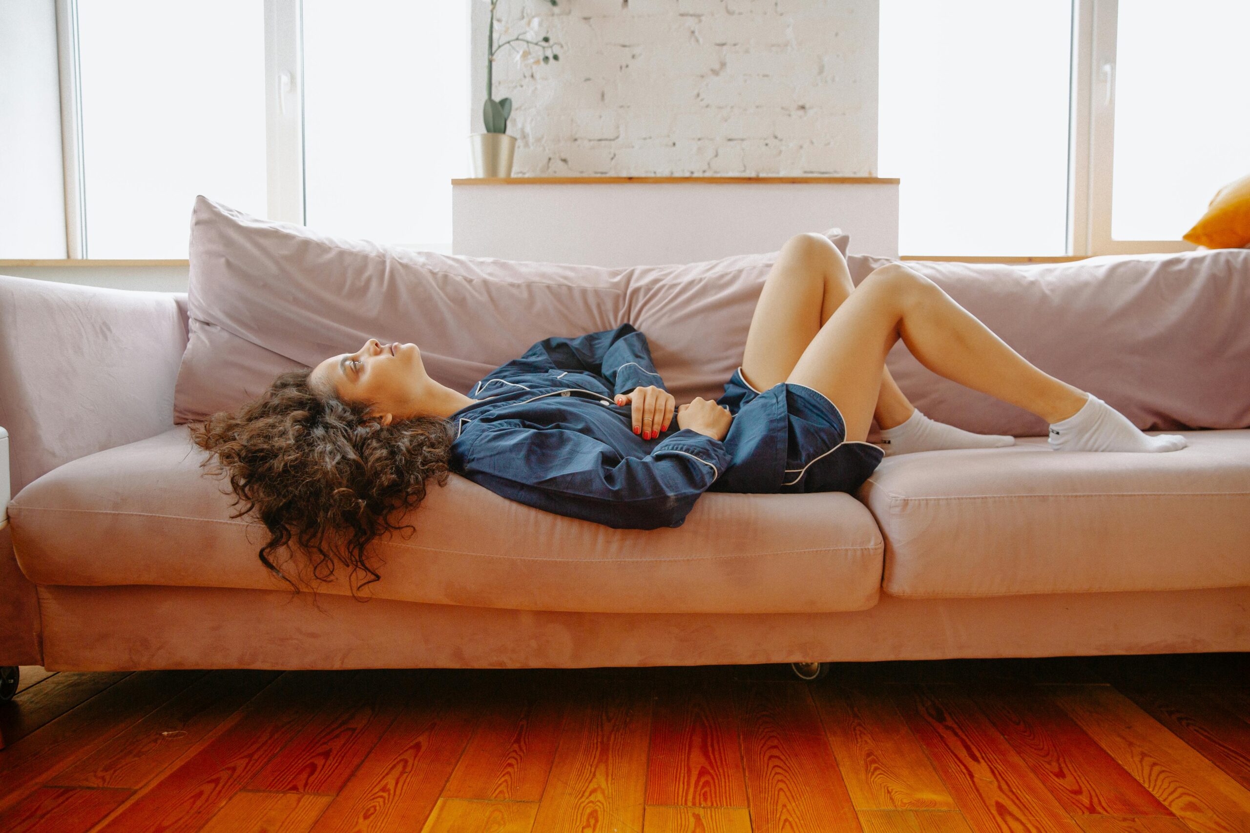 leaky gut symptoms in women - woman lying on couch holding stomach